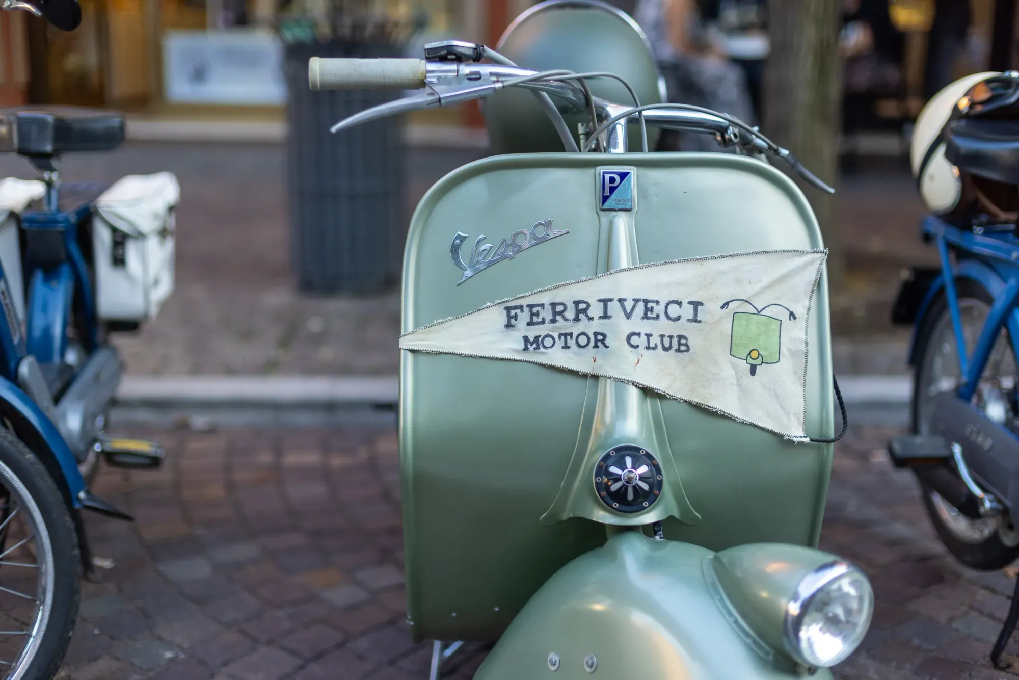 Una Vespa d'epoca verde chiaro con un gagliardetto bianco sullo scudo: «Ferriveci Motor Club».