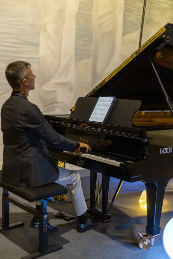 Il pianista al pianoforte, concentrato sulla tastiera.