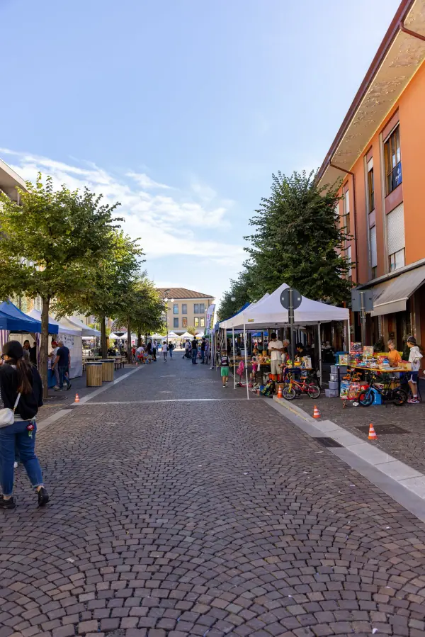 La via del mercatino in verticale, con i gazebo che si perdono in fondo sotto il cielo azzurro.