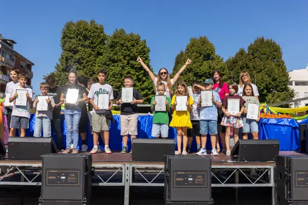Il gruppo dei ragazzi premiati festeggia sul palco con gli attestati, qualcuno con le braccia alzate.
