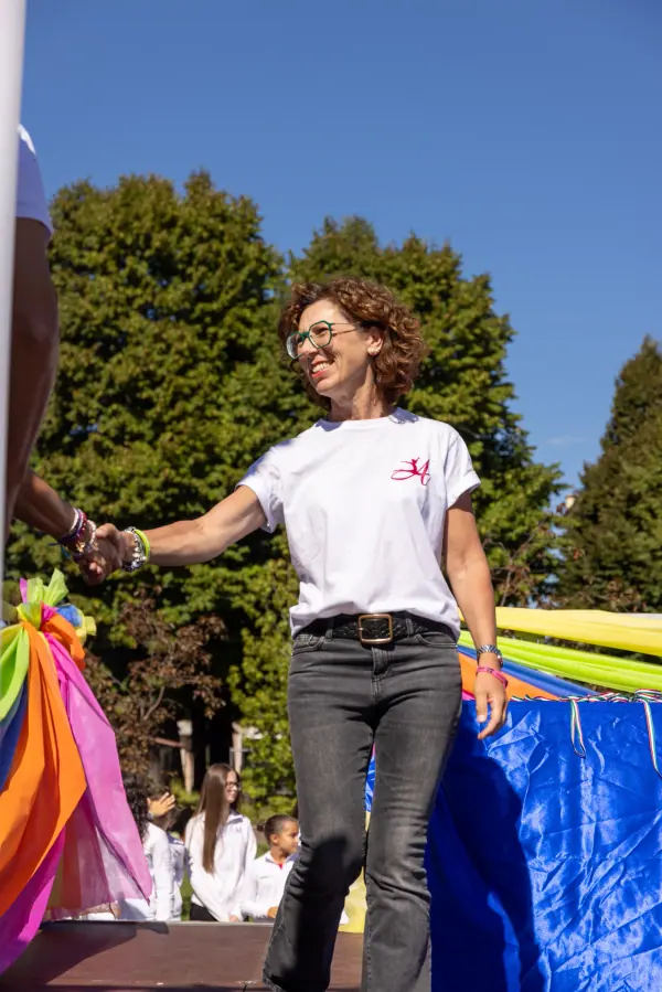 Una premiata sorride e stringe la mano sul palco, davanti ai nastri colorati.